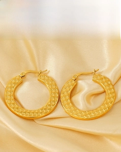Detailed macro view of golden hoop earrings featuring unique textured star patterns