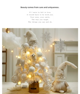 Close-up of white flocked tabletop Christmas tree with knit snowman and LED lights