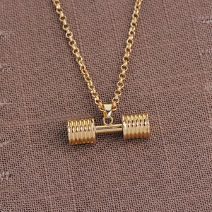 Detailed view of the gold dumbbell pendant with a polished finish on textured fabric