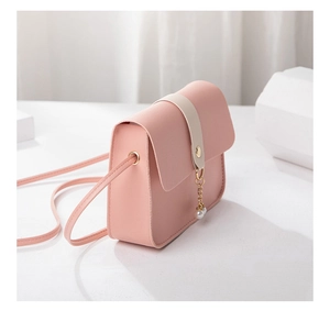Detail of pink crossbody bag with gold hardware, pearl charm and PU leather texture
