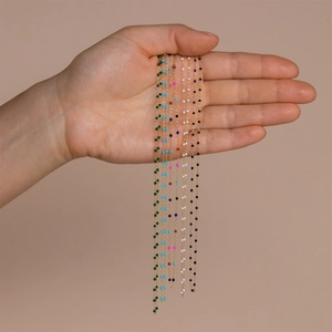 Detail of bohemian gold stainless steel chains with colorful enamel beads held by hand