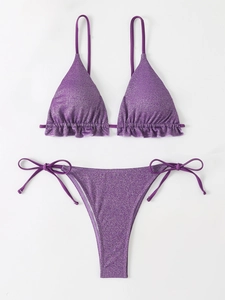 Détail d'un bikini pailleté violet avec bordures volantées et culotte à nœuds latéraux