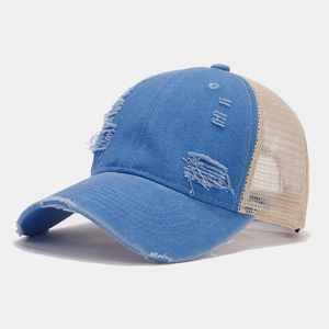 Close-up of distressed blue denim and beige mesh panels on a vintage baseball cap