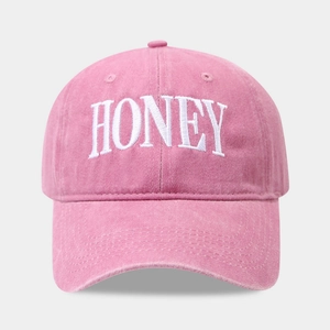 Close-up of HONEY embroidery and vintage washed cotton texture on pink baseball cap