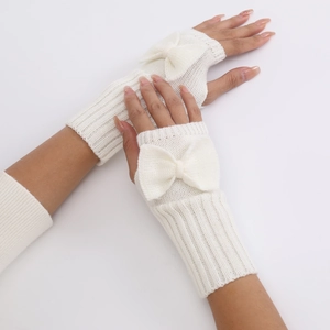 Close-up of cream white knitted fingerless gloves with elegant bow detail for winter