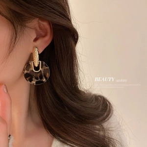 Leopard print acrylic hoop earrings with hammered gold studs on female model