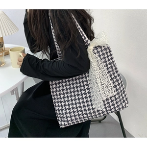 Close-up of houndstooth canvas tote bag featuring a white lace bow in a lifestyle setting