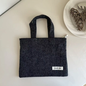Close-up of dark grey herringbone texture tote bag with a Simple Wish fabric label