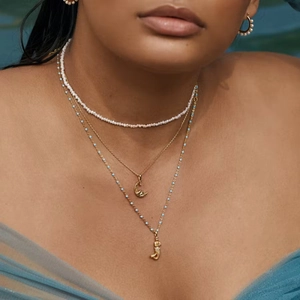 Layered gold crescent moon necklace with pearl choker and turquoise bead pendant charm