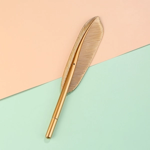 Elegant gold feather-shaped ballpoint pen with detailed metallic textures on soft background