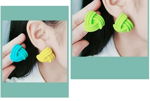 Macro shot of colorful matte spiral knot stud earrings in blue yellow and green