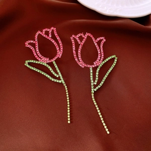 Detailed view of pink crystal tulip flower earrings with green stems on silk background