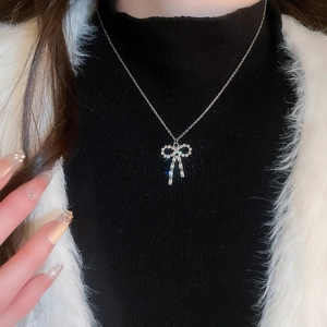 Close-up of a silver bow necklace with sparkling crystals on a model with black sweater