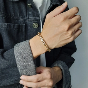 Golden Byzantine chain bracelet for men and women worn with a black denim jacket