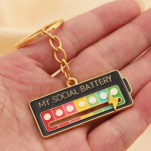 Macro shot of My Social Battery enamel keychain showing battery levels and mood icons