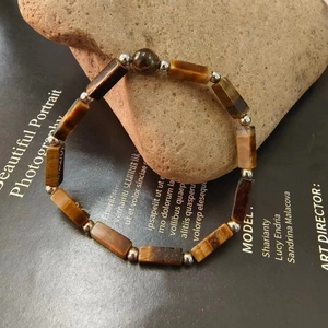 Macro shot of tiger eye stone bracelet with metal beads displayed on a natural rock