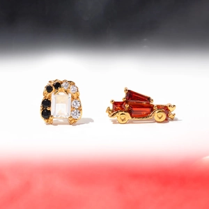 Detail view of gold-plated arch and vintage car earrings with zircon stones