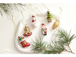 Creative glass Christmas ornaments with pine needles on a white ceramic plate