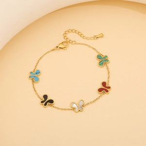 Détail d'un bracelet doré réglable avec cinq breloques papillon colorées en malachite et onyx