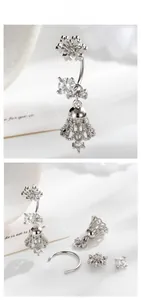 Detailed view of silver snowflake navel ring with cubic zirconia on white fabric