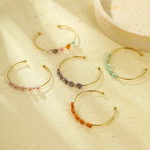 Eleganti bracciali in acciaio al titanio dorato con fiori in zircone su fondo beige