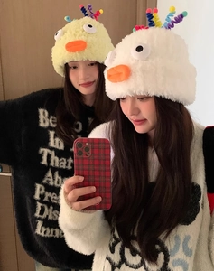 Detail view of cute plush cartoon chick hats in white and yellow colors with ear protection