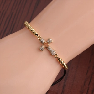 Detail of adjustable gold beaded bracelet with micro-pave zircon cross charm on wrist