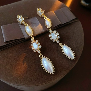 Close-up of vintage gold tassel earrings with pearls and zircons on a brown velvet box