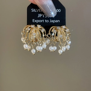 Macro view of luxury fireworks earrings featuring 18k gold plating and pearls