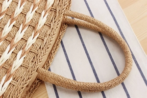 Close-up of handwoven straw tote bag with intricate twill pattern and reinforced handles