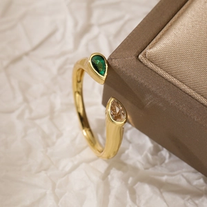 Gold plated open ring with emerald green and champagne pear-cut stones on white paper