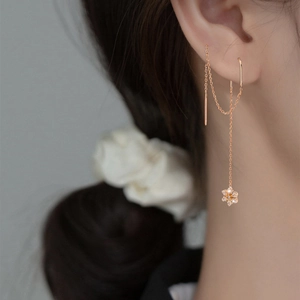 Macro shot of rose gold tassel earrings featuring zirconia flower pendants and delicate chains