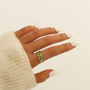 Detail of gold-plated leaf ring with green enamel on a model wearing a knit sweater