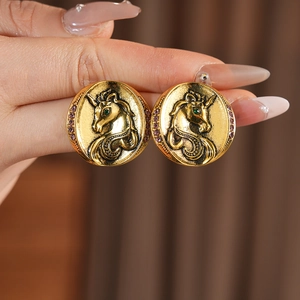 Macro shot of vintage gold unicorn earrings with green eyes and burgundy crystal border