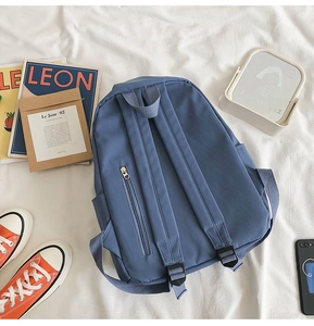 Detailed back view of a blue canvas backpack with wide straps and a hidden anti-theft pocket