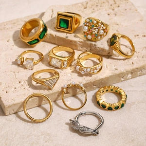 Retro stainless steel rings with green gemstones and pearls on stone display stand