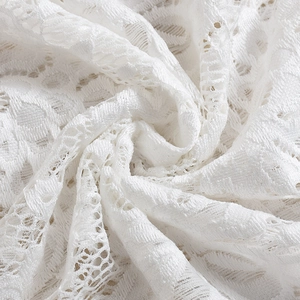 Gros plan détaillé du tissu en dentelle florale blanche montrant les motifs délicats