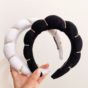 Detailed view of handmade black and white plush headbands with golden beaded accents