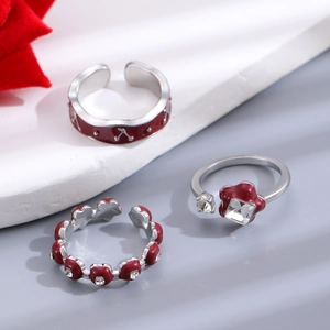 Detailed macro view of three silver open rings with red enamel floral and cherry motifs