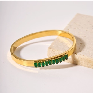 Detailed close-up of 18k gold-plated bangle inlaid with eleven emerald-cut green zircons