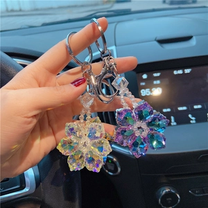 Close-up of hand holding crystal snowflake keychains in clear and blue-purple colors