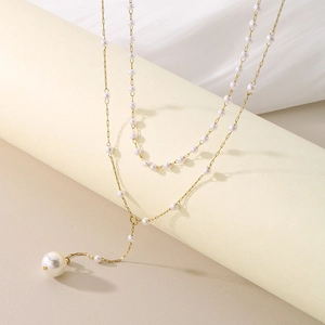 Double-layer pearl necklace with gold chain and pendant on minimalist display