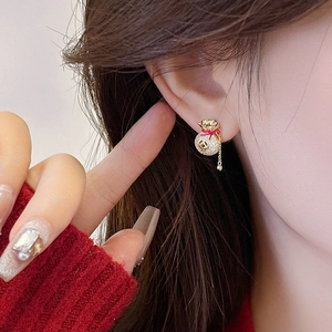 Dettaglio di orecchini con nappa in zircone e design a sacchetto portafortuna su modella