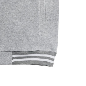 Detail of gray tracksuit jacket showing ribbed hem with white stripes and pocket texture