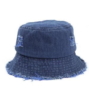 Dettaglio ravvicinato di un cappello pescatore in denim blu con bordi sfrangiati e fori