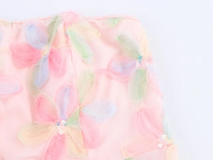 Gros plan sur robe en tulle rose avec broderies florales 3D colorées et sequins brillants
