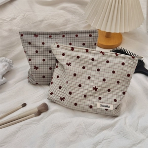 Detailed view of polka dot bow cosmetic bags on a white linen bed with vintage decor