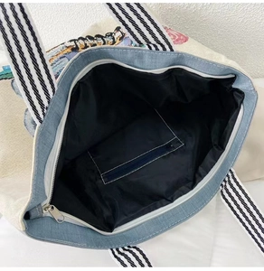 Detailed interior of canvas tote bag showing black lining, zip pocket and metal closure