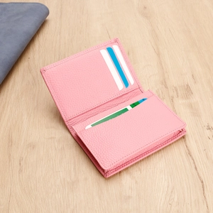 Close-up of pink genuine leather card holder showing multi-slot interior on wooden desk