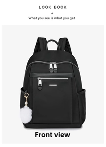 Front view of a minimalist black nylon backpack with silver zippers and a white pompom charm